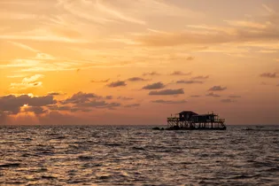 Fisherman's hut in the calm sea at sunset